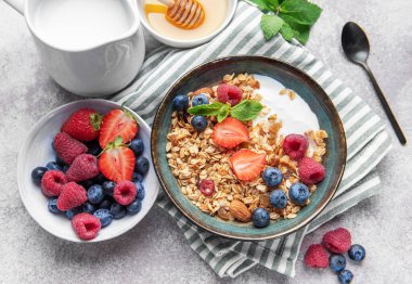Granola ve taze meyve sağlıklı bir kahvaltı veya dokulu bir arka planda atıştırmalık hazırlar.