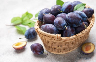 Hasır bir sepeti yapraklarla dolduran erikler olgun meyve ve dilimleri gösteriyor.