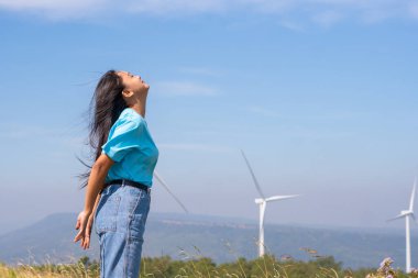 Mavi gökyüzü ve rüzgar türbiniyle özgürlük genç kız, mutlu konsept.