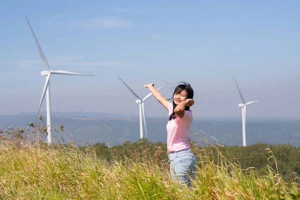 風力タービンと美しい景色を眺めながら山の上に立つ若い女の子 テン電動風力タービンタイ — ストック写真