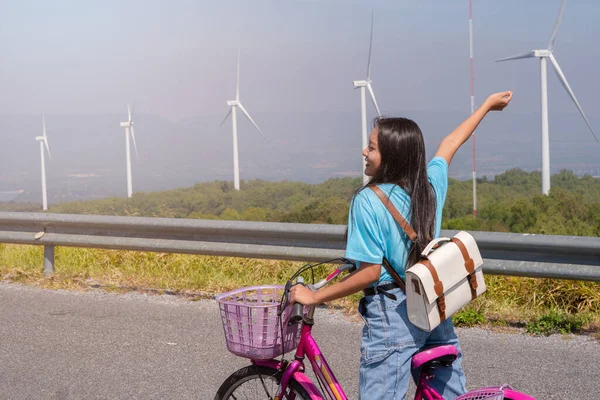 若い女の子は 風力タービン テン電気風力タービンタイで山の道に自転車に乗る — ストック写真