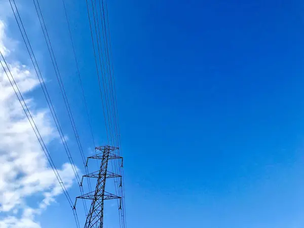 pole electric wires against blue sky cloud background. Electric wires against cloud sky background. Beautiful clouds and blue sky. Electrical pole and organized black color electric wires, lines