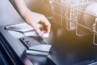 Bulaşık makinesini, modern ev mutfağındaki kirli çatal bıçaklarla otomatik paslanmaz bulaşık makinesine yerleştiren kadın elinin yakın çekimi. Ev işleri, ev işleri.