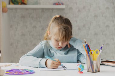 Yorgun, küçük bir kız çocuğu masada oturuyor, ev ödevi yapmaktan acı çekiyor, evde çalışmaktan yorgun, zor bir görevle strese giriyor, sınavlardan önce hazırlanıyor. Evde eğitim, evde eğitim.