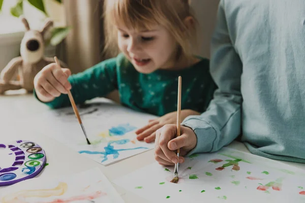 两个可爱的小妹妹或同学用刷子在桌上画画 小女孩在笑 孩子们都在幼儿园或家里 孩子在客厅里家庭教育的概念 做作业 — 图库照片