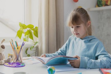 Okullu, küçük, şirin bir kız, elinde kitap, elinde edebiyat, ödevlerini yapıyor, evde ders çalışıyor, sınavlardan önce hazırlanıyor. Evde eğitim, evde eğitim.