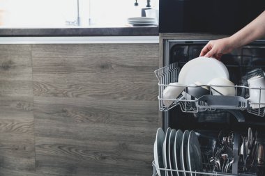 Kadın ellerinin bulaşıkları boşaltması, boşaltması ya da beyaz tabakları alması, modern ev mutfağındaki paslanmaz bulaşık makinesinin bulaşıklarını yıkaması.