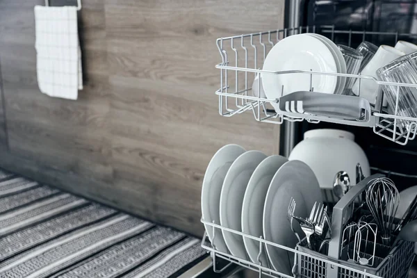 在现代化的家庭厨房里 用干净的器皿把打开的自动不锈钢内置式洗碗机封闭起来 金属叉和刀具 家务活 — 图库照片