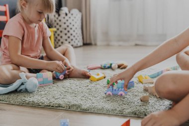 Renkli plastik oyuncak renkli trenle oynayan çocuklar. Çocuklar güneşli beyaz yatak odasında ya da anaokulunda halının üzerinde oturuyorlar. Çocuk için eğlenceli bir çevre dostu oyun