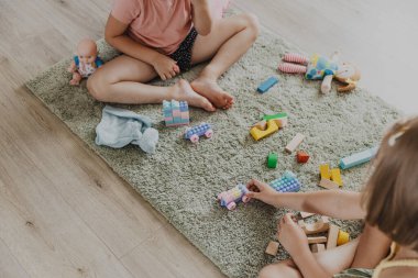 Renkli plastik oyuncak renkli trenle oynayan çocuklar. Çocuklar güneşli beyaz yatak odasında ya da anaokulunda halının üzerinde oturuyorlar. Çocuk için eğlenceli bir çevre dostu oyun