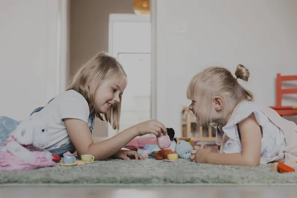 カラフルなおもちゃセットでティーパーティーをする女性の子供たちのクローズアップ 幼稚園 保育園でカーペットの上に横たわっている子供たち 教育環境に優しい子供のゲーム モータースキルの開発 想像力 — ストック写真