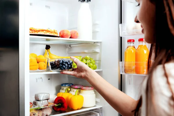 Kadın el ele tutuşuyor, açık buzdolabı rafından yabanmersini alıyor ya da içi meyve, sebze, muz, şeftali ve yoğurt dolu buzdolabı çekmecesi alıyor. Sağlıklı beslenme, yaşam tarzı konsepti