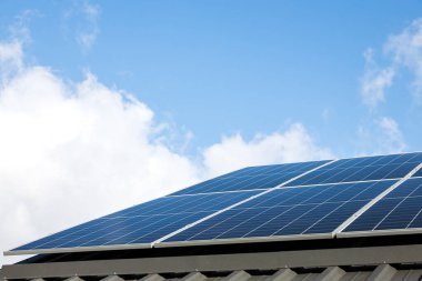 Bulutlu mavi gökyüzüne karşı güneş paneli hücrelerinin hava görüntüsü. Alternatif enerji kavramı, sürdürülebilir kaynaklar. Güneş panelleri olan ev tek başına fotovoltaik bitki sistemi. Profesyonel kurulum