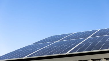 Açık mavi gökyüzü arkaplanındaki güneş paneli hücrelerinin hava görüntüsü. Temiz alternatif enerji konsepti, sürdürülebilir kaynaklar. Modern ev, güneş panelleri çatıda tek başına fotovoltaik santral sistemi