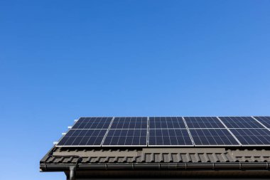 Güneş panelleri olan ev fotovoltaik fabrika sistemi profesyonel olarak metal çatıya monte edilmiş, yeşile dönüyor. Açık mavi gökyüzü arkaplanı. Temiz alternatif enerji güç kavramı, sürdürülebilir kaynaklar