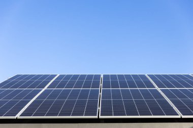 Açık mavi gökyüzü arkaplanındaki güneş paneli hücrelerinin hava görüntüsü. Temiz alternatif enerji konsepti, sürdürülebilir kaynaklar. Modern ev, güneş panelleri çatıda tek başına fotovoltaik santral sistemi