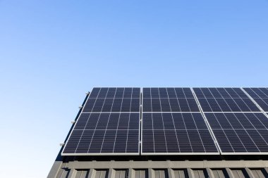 Evdeki metal yaprak çatıdaki güneş panelleri tek başına fotovoltaik tesis sistemine sahip modern bir ev. Açık mavi gökyüzü arkaplanı. Temiz alternatif enerji güç kavramı, sürdürülebilir kaynaklar