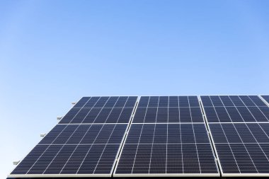 Açık mavi gökyüzü arkaplanındaki güneş paneli hücrelerinin hava görüntüsü. Temiz alternatif enerji konsepti, sürdürülebilir kaynaklar. Modern ev, güneş panelleri çatıda tek başına fotovoltaik santral sistemi