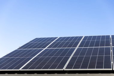 Açık mavi gökyüzü arkaplanındaki güneş paneli hücrelerinin hava görüntüsü. Temiz alternatif enerji konsepti, sürdürülebilir kaynaklar. Modern ev, güneş panelleri çatıda tek başına fotovoltaik santral sistemi