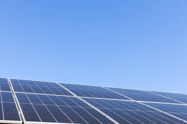 Evdeki metal yaprak çatıdaki güneş panelleri tek başına fotovoltaik tesis sistemine sahip modern bir ev. Açık mavi gökyüzü arkaplanı. Temiz alternatif enerji güç kavramı, sürdürülebilir kaynaklar