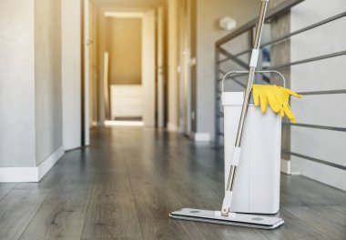 Temizlik malzemeleri: paspas, eldiven, hamurlu kova modern oturma odasındaki ahşap kaplama zemin, ıslak teçhizat aletleri, temizlik konsepti. Ev temizliğini, temizliği, hijyeni vurgulamak