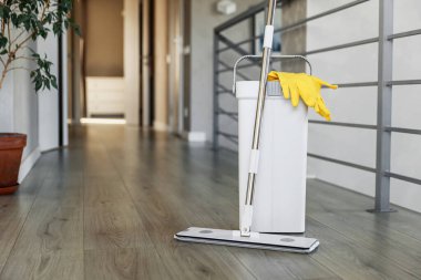 Temizlik malzemeleri: paspas, eldiven, hamurlu kova modern oturma odasındaki ahşap kaplama zemin, ıslak teçhizat aletleri, temizlik konsepti. Ev temizliğini, temizliği, hijyeni vurgulamak