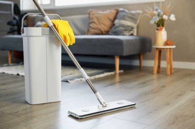 Temizlik malzemeleri: paspas, eldiven, hamurlu kova modern oturma odasındaki ahşap kaplama zemin, ıslak teçhizat aletleri, temizlik konsepti. Ev temizliğini, temizliği, hijyeni vurgulamak