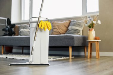 Temizlik malzemeleri: paspas, eldiven, hamurlu kova modern oturma odasındaki ahşap kaplama zemin, ıslak teçhizat aletleri, temizlik konsepti. Ev temizliğini, temizliği, hijyeni vurgulamak