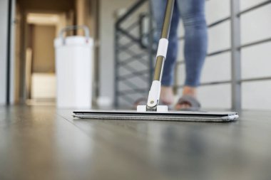 Modern ev ortamında yerleri paspaslayan, parlak ahşap silen bir kadın. Ev hanımı rahat oturma odasında temizlik bezi kullanır. Oda servisi, ev işi. Temizlik, temizlik, temizlik, temizlik, bakım.