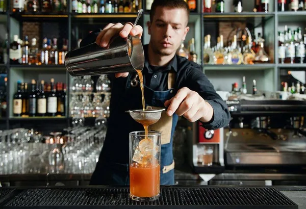 Barman prepairing fresh cocktail in cocktail bar