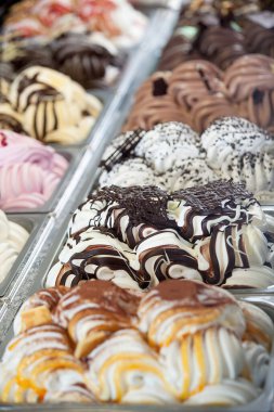 Metal tepsilerde sergilenen yaz paketleri gibi çeşitli dondurma tatları satan bir mağazada veya dondurmacıda pencereyi göster