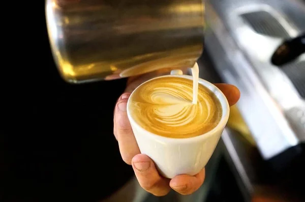 Mężczyzna Barista Trzyma Filiżankę Kawy Jego Ręce Wylewając Mleko Latte — Zdjęcie stockowe