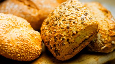 Ahşap masada farklı türde taze ekmek. Kahverengi arka planda münferit bir ekmek çeşidi. Kaydırıcı atışı.