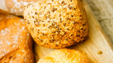 Ahşap masada farklı türde taze ekmek. Kahverengi arka planda münferit bir ekmek çeşidi. Kaydırıcı atışı.