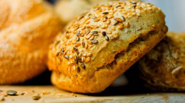 Ahşap masada farklı türde taze ekmek. Kahverengi arka planda münferit bir ekmek çeşidi. Kaydırıcı atışı.