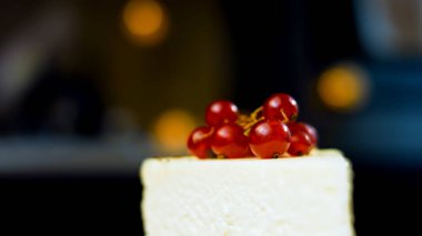 Frenk üzümlü bir dilim peynirli kek. Makro ve kaydırma atışı. Arka planda bir retro atmosfer var..