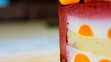 Çilekli, beyaz ve kırmızı kirazlı bir dilim pasta. Pastanın özel bir kubbesi var. Makro ve kaydırma atışı. Arka planda bir retro atmosfer var..