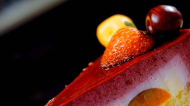 Çilekli, beyaz ve kırmızı kirazlı bir dilim pasta. Pastanın özel bir kubbesi var. Makro ve kaydırma atışı. Arka planda bir retro atmosfer var..