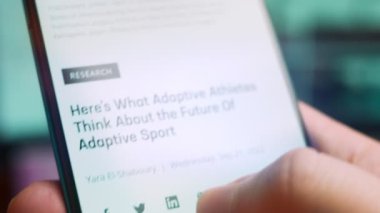 Smartphone in hand, macro view of the adaptive athlete question.