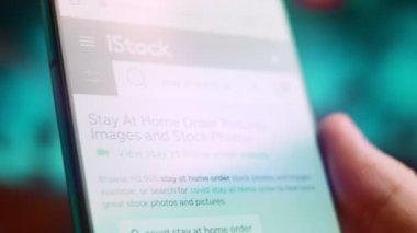 Smartphone in hand, macro view of the stay at home question.