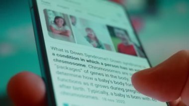 Smartphone in hand, looking for information about down syndrome.