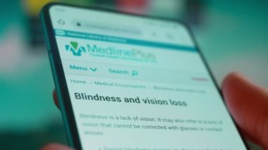 Smartphone in hand, looking for information about blindness.