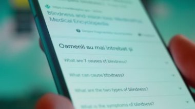 Smartphone in hand, looking for information about blindness.