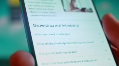 Smartphone in hand, looking for information about working from home.