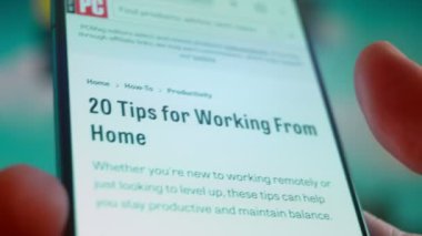 Smartphone in hand, looking for information about working from home.