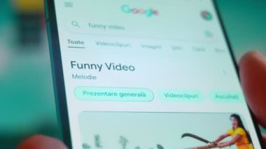 Smartphone in hand, looking for information about funny videos.