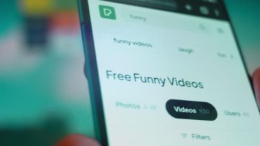 Smartphone in hand, looking for information about funny videos.
