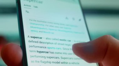 Smartphone in hand, looking for information about the super car.