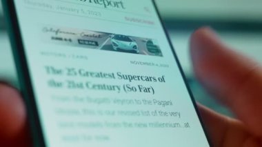 Smartphone in hand, looking for information about the super car.