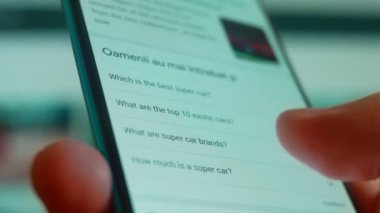 Smartphone in hand, looking for information about the super car.